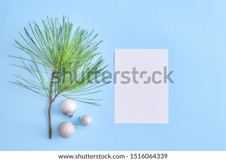 Mockup white greeting card with pine branches and balls on a blue background