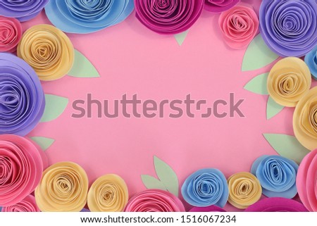 Pastel colored paper craft rose flat lay background with flowers and leaves around the endges and pink empty copy space in middle