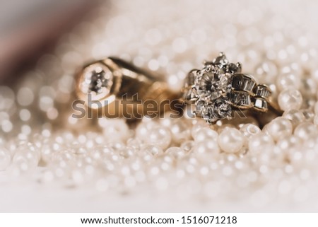 Pair of gold wedding rings with diamonds on pearl background with bokeh,Vintage picture style