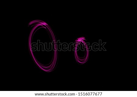 Long exposure photograph of the letter o in upper case and lower case, in neon pink colour in an abstract swirl, parallel lines pattern against a black background. Light painting photography.