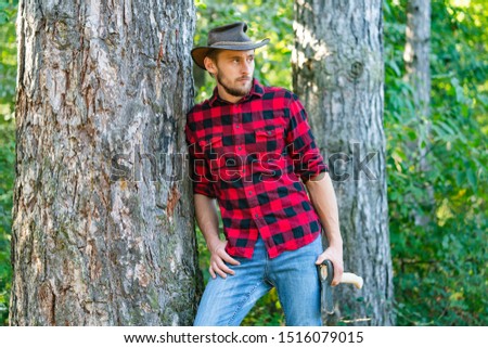 Lumberjack worker walking in the forest with axe. Lumberjack worker standing in the forest with axe. Lumberjack holding the axe. Lumberjack with axe on forest background
