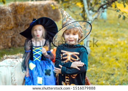 Two kids like skeleton or witch Ready for Trick or Treat. Surprised group little zombie in Halloween costume eating treat, calaverita sweets candles