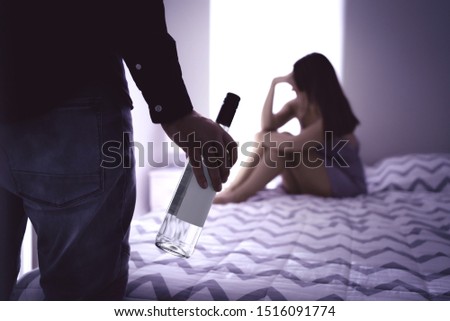 Drunk man and sad upset woman. Alcohol problem and alcoholism in relationship concept. Drunken alcoholic husband with bottle. Wife crying. Couple fighting home at night. Fear and stress in family. Royalty-Free Stock Photo #1516091774