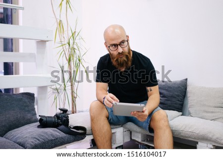 A man with beard retouching photography in tablet