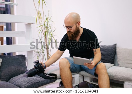A man with beard retouching photography in tablet