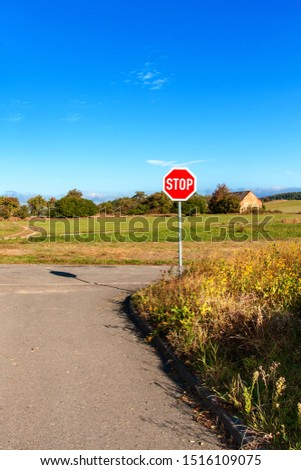 Stop road sign at rural intersection. Transport safety. Environment. Warning symbol. Obligation to stop the vehicle.