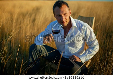 Handsome mature man tasting glass of red wine outdoor.