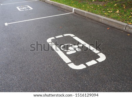 Parking lot with white painted handicapped symbol of wheelchair on asphalt, parking spaces for disabled visitors. Empty disabled parking space. Free parking sign for disabled people's car.