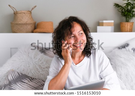 A woman with a laptop is sitting on the bed. Modern business lady at home. Photo in light colors