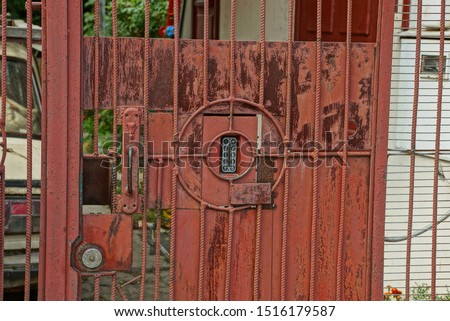old red metal gate with gray combination lock on the street