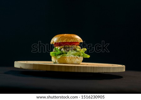 Delicious big cheeseburger with salad black background
