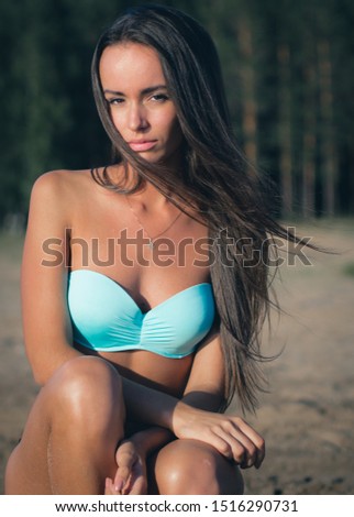 young woman in a turquoise swimsuit near the water sunbathing on the beach.