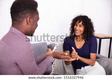 Man And Woman Communicating With Sign Languages Sitting On Sofa