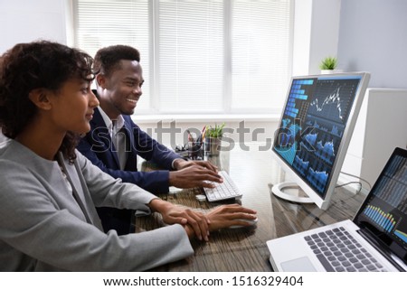 Stock Market Broker Analyzing Graphs On Computer In Office