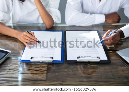 Two Businesspeople Working On Contract Paper In Office