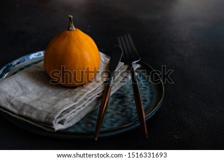 Autumnal table setting with ripe pupking for Thanksgiving holiday dinner