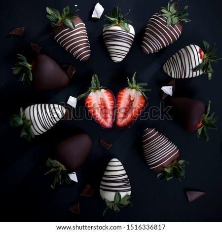 group of chocolate covered strawberries in a heart shape, valentines day dessert, sliced strawberry with whole dark and white chocolate covered strawberries, dark background
