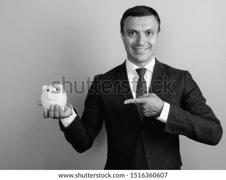 Businessman wearing suit against gray background shot in black and white