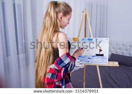 Beautiful woman artist painter with brushes and oil canvas posing bed at room.