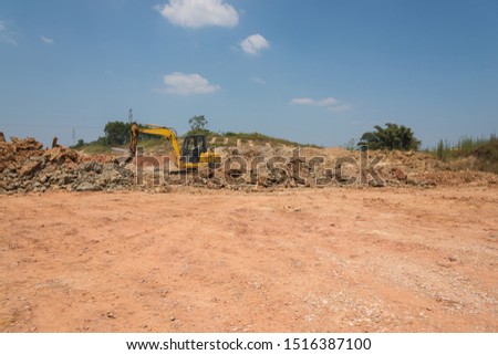 a dry soil and a small excavator at the road construction site