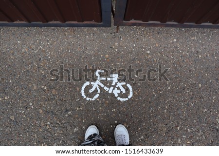 There is a pictogram of bicycle drawn in white paint on asphalt top view.