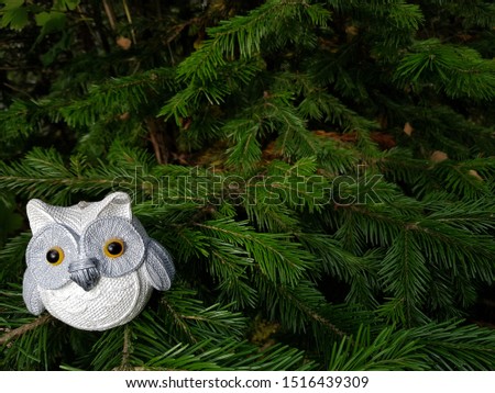 Bauble figurines of owl. Christmas retro sparkle decoration on a spruce branch. Holiday background with a copy space. Suitable for greeting cards, banners and posters.