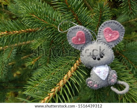Christmas felt decoration on a spruce branch. Handmade bauble figurines symbol of the year - mouse. Holiday background with a copy space. Suitable for greeting cards, banners and posters.