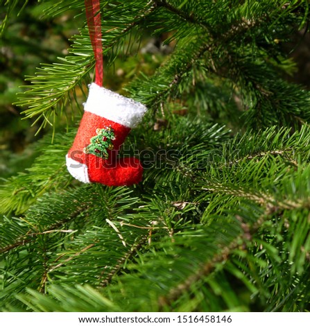 Christmas felt decoration on a spruce branch. Handmade bauble figurines a sock. Holiday background with a copy space. Suitable for greeting cards, banners and posters.