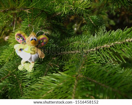 Christmas felt decoration on a spruce branch. Handmade bauble figurines a butterfly. Holiday background with a copy space. Suitable for greeting cards, banners and posters.