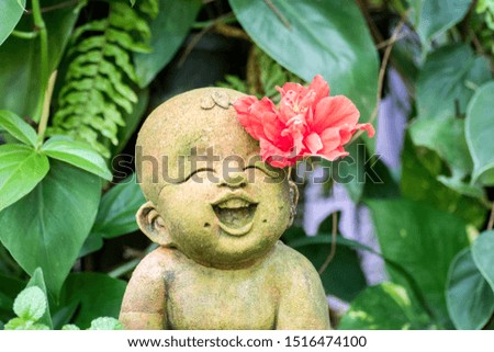Cute sculpture of a happy child with a red flower behind his ear. 