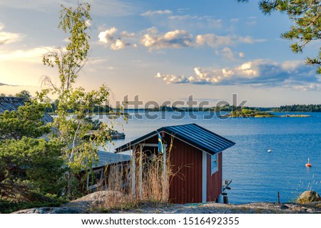 Sweden, East Coast. A beautiful summer day by the sea with small, red fishing huts. Royalty-Free Stock Photo #1516492355