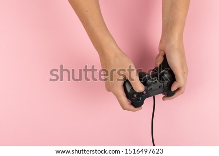 Female hands hold a gamepad on pink background. Weekend concept, gaming hobby. Copy space.