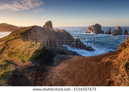 Sunset view from los urros at spain, north atlantic coastline. Backlight sunlight lighting the ocean and harsh cliffs. hiking person enjoying the wide magic view.