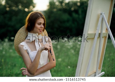 woman with a brush in her hand looks at a white canvas young artist