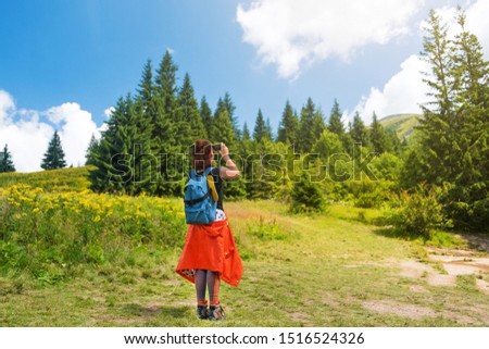 Woman wanderlust photographing scenery nature landscape on smartphone in the forest. Young female taking photo on cellular. Nature photographer tourist shoots while standing on top of the mountain.
