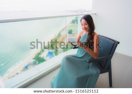 Beautiful portrait young asian woman  reading book at outdoor balcony with sea ocean view background