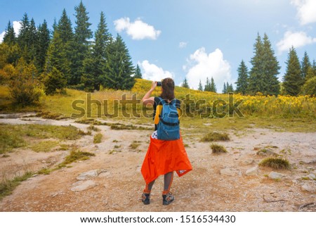 Woman wanderlust photographing nature landscape on smartphone in the forest. Young female taking photo. Nature photographer tourist shoots, happy traveler. Carpathian mountains, Hoverla, Ukraine.