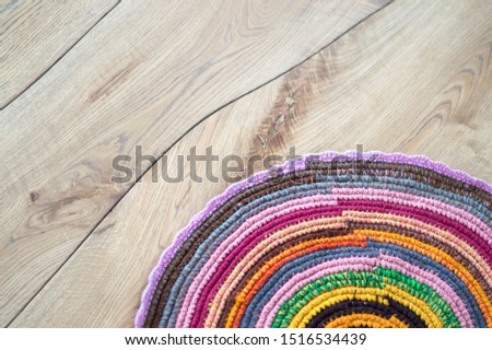Hand made crocheted bright round rug on natural solid wood floor