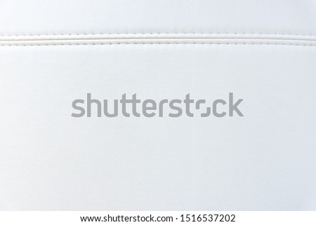 Background with white artificial leather, close up photo image. Photo picture of white eco leather. Coarse - grained texture. Stitched eco-leather seat upholstery.