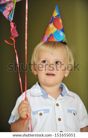  little boy with birthday hat play with balloons