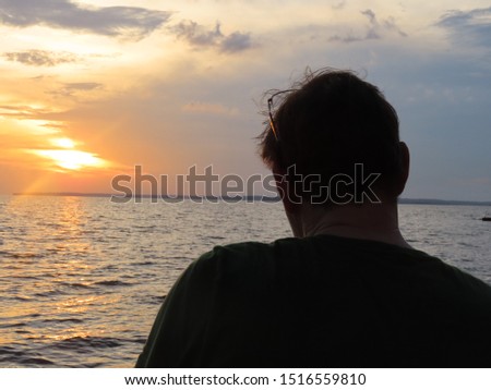 50-year-old man in denim shorts and T-shirt photographing the Rio Negro on Ponta Negra beach in Manaus, the Amazon region, in the late afternoon