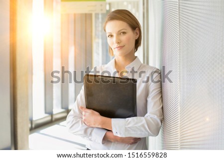 Portrait of young attractive businesswoman holding business leather folder with yellow lens flare