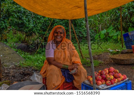  stock photo of 50 to 60 age group Indian women wearing  yellow color saree, selling farm fresh red apple in the village weekly bazaar or market at Kolhapur, Maharashtra, India. selective focus.