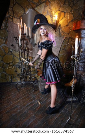 Witch with broom . Girl in makeup and witch costume on Halloween in an ancient castle by candlelight . Vertically. 