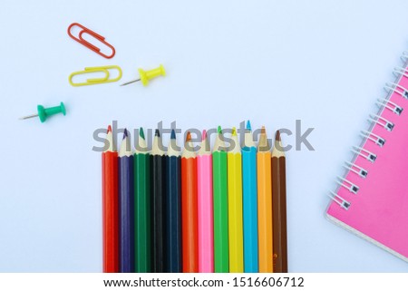 Notepad with set of colorful paper clips on white background.business creativity concepts Colored pencils.Flat lay design