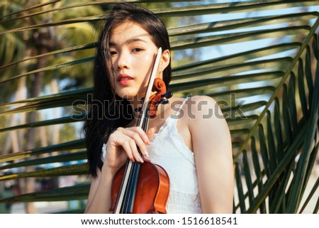 Portrait of woman and violin with coconut leaf on background.