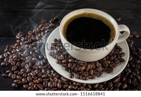 Needle black coffee in a cup of coffee placed on the coffee beans. That are currently roasting Fresh roasted coffee concept