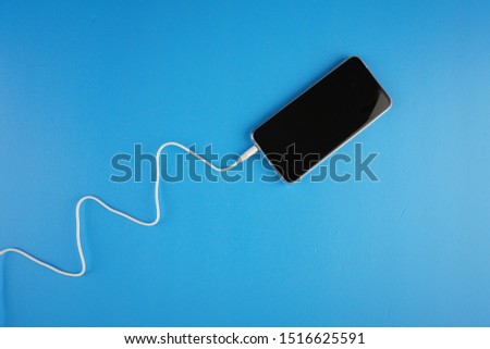 Wave shape of white cable attached on smartphone over blue background