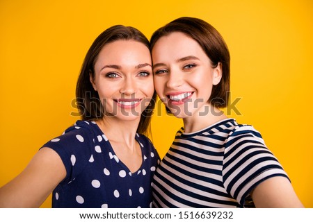 Close up photo of two amazing ladies making selfies toothy beaming smiling wear summer casual trendy t-shirts isolated yellow background