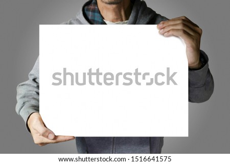 Man with gray hood jacket holding the white sign empty space for text on gray background color.